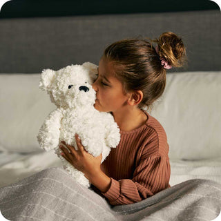 Cream Curly Bear Warmies
Child holding a white teddy bear on a couch