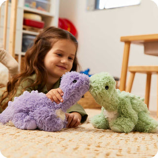 Purple Long Neck Dinosaur Warmies
Green Long Neck Dinosaur Warmies
Child playing with two plush dinosaurs, a purple one and a green one, on a bed.