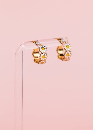 Pierced Co. Huggies - Daisy
Gold hoop earrings with white and yellow daisy flower charms, displayed on a clear acrylic stand against a solid pink background.