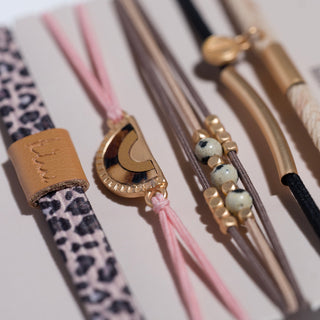 K'lani "Wild" Animal Print with Pink Accent Hair Tie Bracelets
Leather-bound straws with decorative ends on a light background