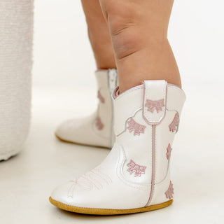 White and pink bow cowgirl baby booties by Wild & Rae with cute bow accents, perfect for little cowgirl outfits.