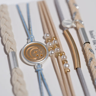 K'lani "Wonder" Soft Creams and Blues with Pearls and Gold Hair Tie Bracelets
Collection of hair ties with decorative elements on a light background