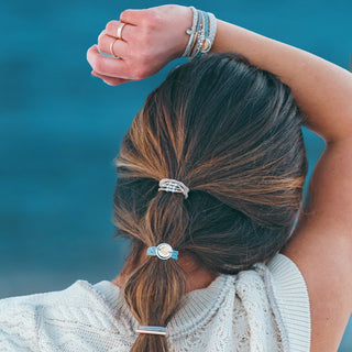 K'lani "Wonder" Soft Creams and Blues with Pearls and Gold Hair Tie Bracelets
Person with braided hair wearing multiple bracelets against a blue background