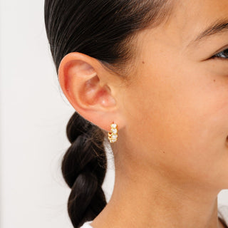 Pip Pop Post Earrings - Heart Gem Hoop Diamond
A close-up of a person's ear wearing a small gold huggie hoop earring adorned with clear rhinestones.
