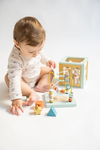 Kalencom Multi-Activity Cube
Baby playing with wooden toys on a white surface