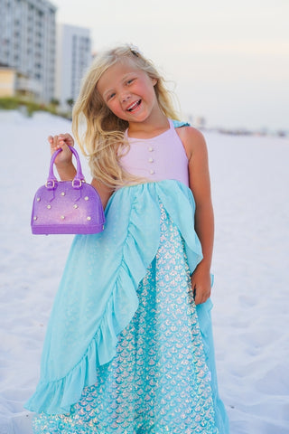 Carrying Kind Rhinestone Cate Handbag - Purple Sparkle
Young girl in a light blue dress holding a purple handbag with a cityscape in the background.