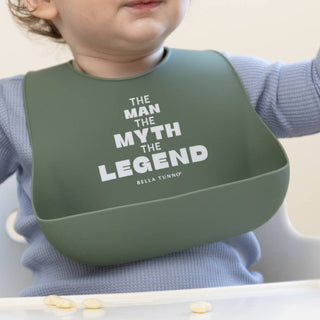 Bella Tunno Wonder Bib - Man Myth Legend
A close-up of a baby wearing a sage green silicone bib with white text that reads 'THE MAN THE MYTH THE LEGEND' and 'BELLA TUNNO'. The baby is wearing a light blue ribbed long-sleeve shirt and sitting in a white high chair.