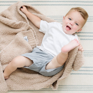 Saranoni Bamboni® Receiving Blanket - Birch
Baby lying on a beige blanket with a striped background