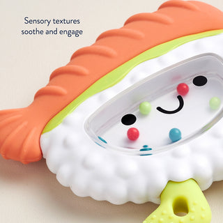 Itzy Ritzy Sweetie Shake Plus Teething + Rattle Toy - Sushi Sensory toy with textured surface and smiley face design on a light background