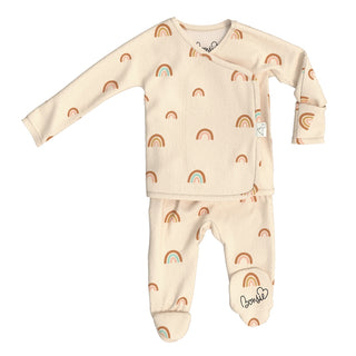 Bonsie Footie - Little Wishes
A baby footed sleeper set consisting of a long-sleeve wrap top and matching pants in a warm cream color, decorated with a repeating pattern of small brown and orange rainbows with light blue centers. The brand name 'bonnet' is printed in black script on the ankle of the pants.