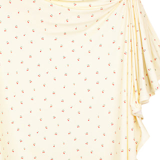 Lou Lou and Company Swaddle Blanket - Sadie
A draped cream-colored fabric top with a small all-over cherry print, featuring a draped neckline and side ruffles, shown against a plain white background.