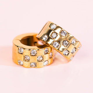 Pierced Co Huggies earrings with chunky checkered diamond pattern, gold-tone metal, and pierced post design.