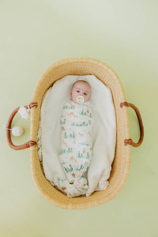 Copper Pearl Grayson Swaddle Blanket
Baby swaddled in a patterned blanket lying in a woven basket on a light green background