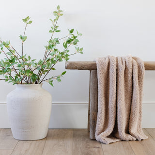 Saranoni Bamboni® Receiving Blanket - Birch
Vase with green branches and beige towel on a wooden bench against a white wall.