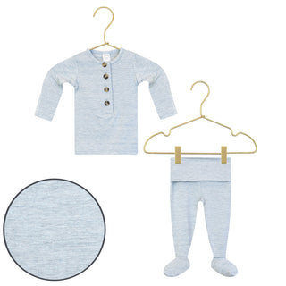 Lou Lou and Company Top and Bottoms - Crew
Baby long-sleeve henley shirt and footed pajama set in light heathered blue, shown on gold hangers with a circular fabric texture inset on a white background.