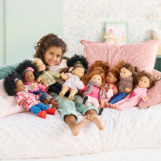 Corolle Maelys 14" Doll
Child with a collection of dolls on a bed