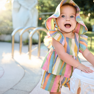 Pink Chicken Baby Girls Elsie 2pc Set - Parade Stripe
Child wearing a colorful striped dress and sun hat outdoors