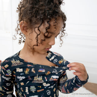 Magnetic Me Harry Potter First Year Modal L/S Pajama Set
Child wearing a dark blue shirt with animal prints, looking at something in their hands.