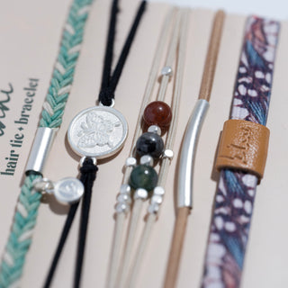 K'lani "Flourish" Natural Butterfly Hair Tie Bracelets
Collection of hair ties with various designs and colors on a beige background