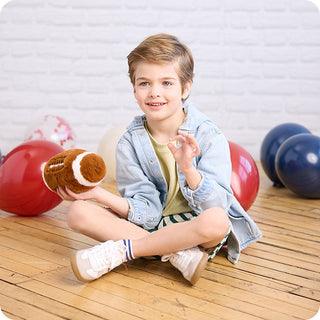 Football Warmies
Child sitting on a wooden floor holding a plush toy with balloons in the background