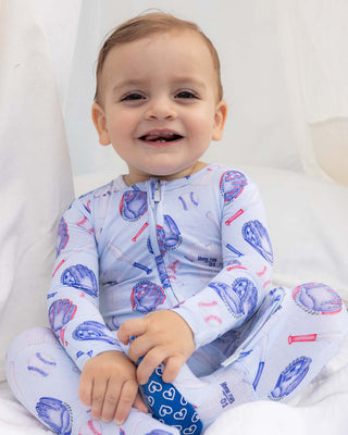Lev Baby Zippered Footie - Home Run
Baby wearing a patterned onesie sitting on a white blanket