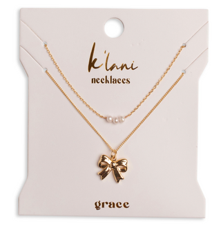 K'lani "Grace" Gold Bow with Pearl Accent Necklace Set
A gold-tone double-strand necklace set on a cream-colored display card. The top necklace has three small white pearls, and the bottom necklace features a polished gold bow pendant.