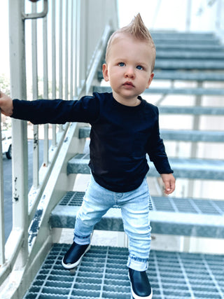 Little Bipsy Long Sleeve Pocket Tee - Black
Child in a navy sweater and light blue jeans standing on metal stairs.