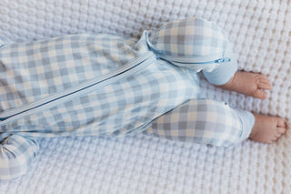 In My Jammers Blue Gingham Zipper Romper
Baby in blue checkered outfit lying on a textured surface