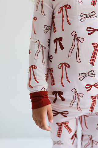 In My Jammers Merry Little Bows Two Piece Set
Close-up of a person wearing pajamas with bow pattern on a plain background