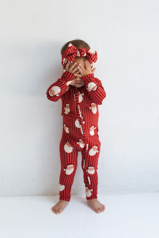 In My Jammers Santa Zipper Romper
Child wearing a red pajama set with Santa Claus pattern on a white background