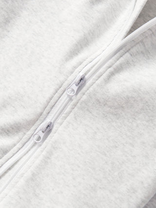 Little Bipsy 2-Way Zip Romper - Light Heather Grey
Close-up of a zipper on a textured white fabric background