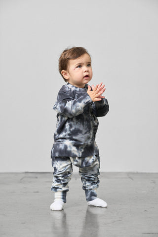Little Bipsy Marble Pullover - Blue
Child wearing a tie-dye outfit standing on a gray floor with a white background