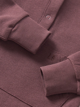 Little Bipsy Waffle Romper - Huckleberry
Close-up of a textured purple sweater with button details