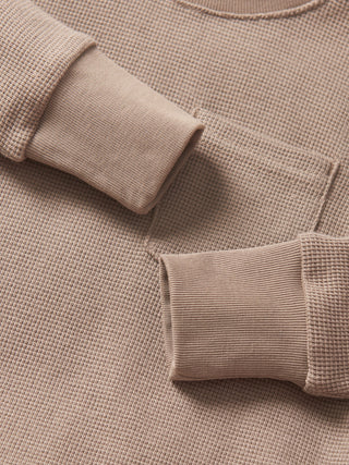 Little Bipsy Waffle Top - Mushroom
Close-up of a beige textured sweater with rolled-up sleeves.