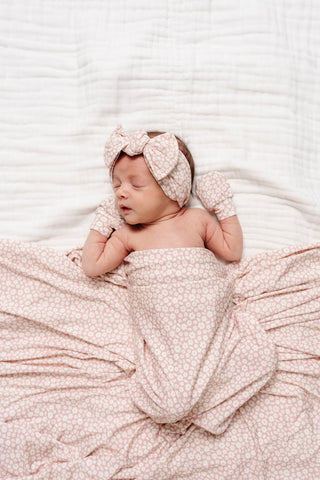 Lou Lou and Company Headband - Flora
Newborn baby wrapped in a pink blanket with a matching headband on a white background