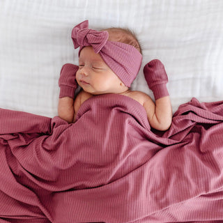 Lou Lou and Company Ribbed Headband - Marjorie
Newborn baby wrapped in a pink blanket with matching headband and mittens on a white background