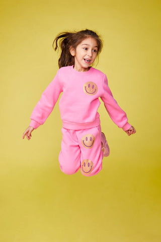 Mini Dreamers Naomi Crystal Smiley Face Sweatshirt and Sweatpant Set
Child wearing a pink outfit with smiley face designs on a yellow background