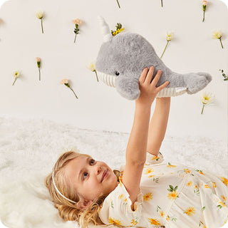 Narwhal Warmies
Child holding a plush whale toy with flowers in the background