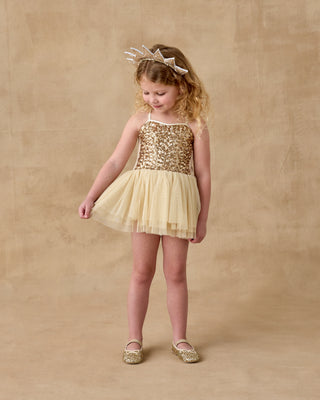 Noralee Clementine Tutu - Champagne
Young girl wearing a gold sequin dress and matching shoes on a beige background