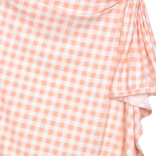Lou Lou and Company Evie swaddle blanket in peach gingham fabric, soft and cozy for newborns and infants.