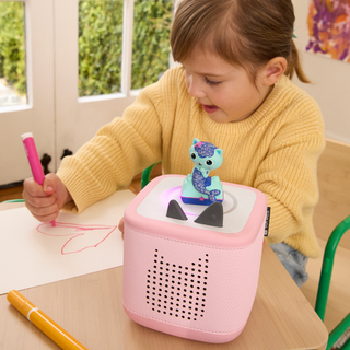 Tonies Character - Dreamworks: Gabby's Dollhouse: MerCat
Child playing with a pink toy device on a table, surrounded by drawing materials.