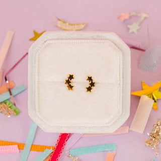 Pierced Co. Triple Star Earrings
Pair of star-shaped earrings on a white square pad with colorful ribbons and decorative items in the background.