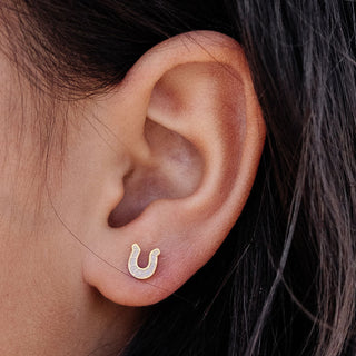 Pip Pop Post Earrings - Horseshoe Stud
Close-up of an ear wearing a gold horseshoe-shaped earring with small stones.