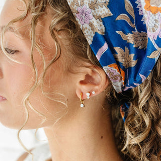 Pip Pop Post Earrings - Opal Dual Stud
Close-up of a person wearing a colorful headscarf with floral patterns.