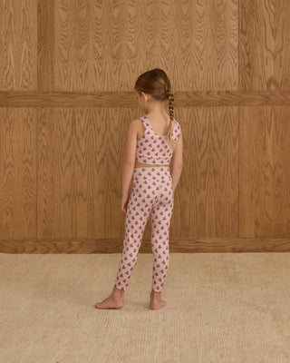 Play by Rylee & Cru Swift Sports Bra - Blush Fleur Play by Rylee & Cru Basic Legging - Blush Fleur Young girl wearing a patterned outfit standing against a wooden wall.