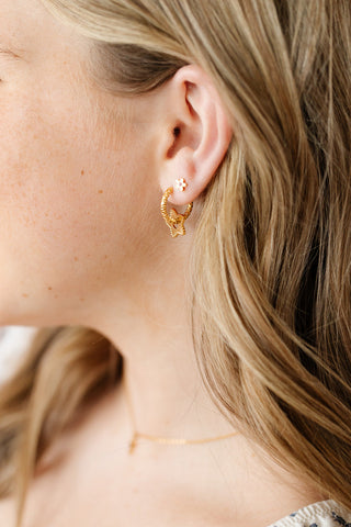 Pip Pop Post Gold Star Braided Hoops
Close-up of a person wearing gold hoop earrings with a blurred background