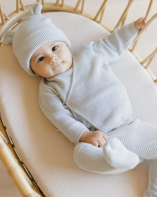 Quincy Mae Baby Bear Beanie - Ice Blue
Baby in a light gray outfit lying in a crib