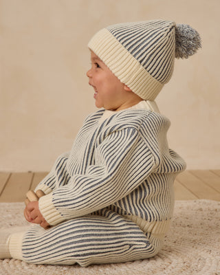Quincy Mae Beanie - Ocean
Child wearing a striped sweater and hat on a wooden floor with a beige background