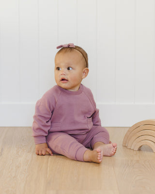 Quincy Mae Pocket Sweatshirt & Sweatpant Set - Mulberry
Baby in a pink outfit sitting on a wooden floor with a white wall background