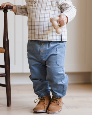 Quincy Mae Zion Shirt - Blue Plaid
Child wearing a plaid shirt, blue pants, and brown shoes standing next to a wooden chair.